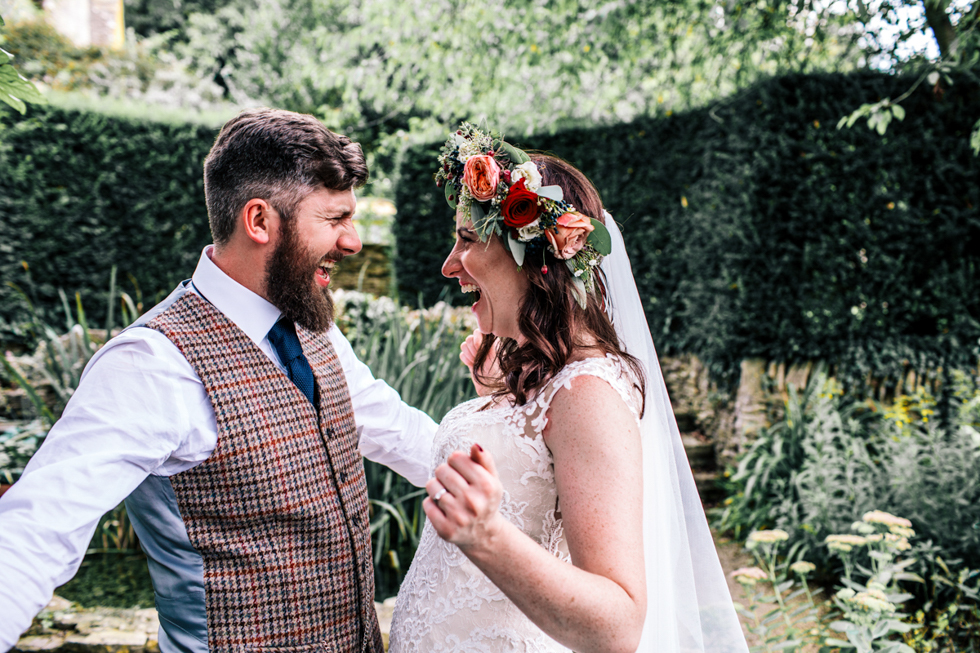 quirky bride and groom laughing together during couple portraits outside at Owlpen Manor