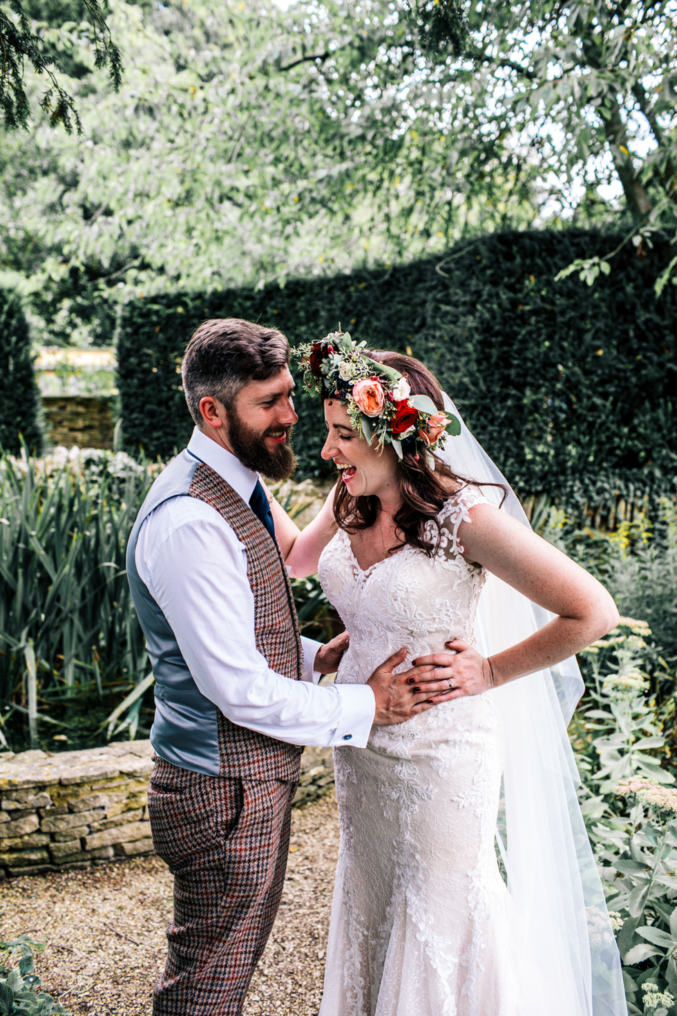 quirky bride and groom laughing together during couple portraits outside at Owlpen Manor