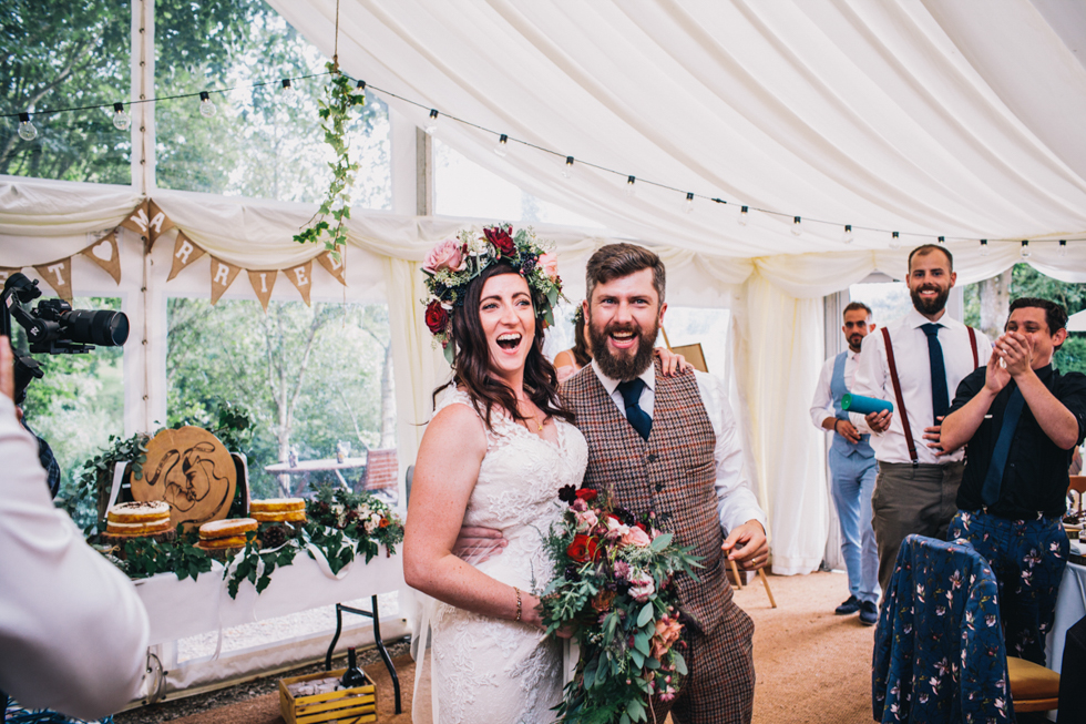 quirky bride and groom entering the wedding reception in style together laughing and having fun at Owlpen manor 