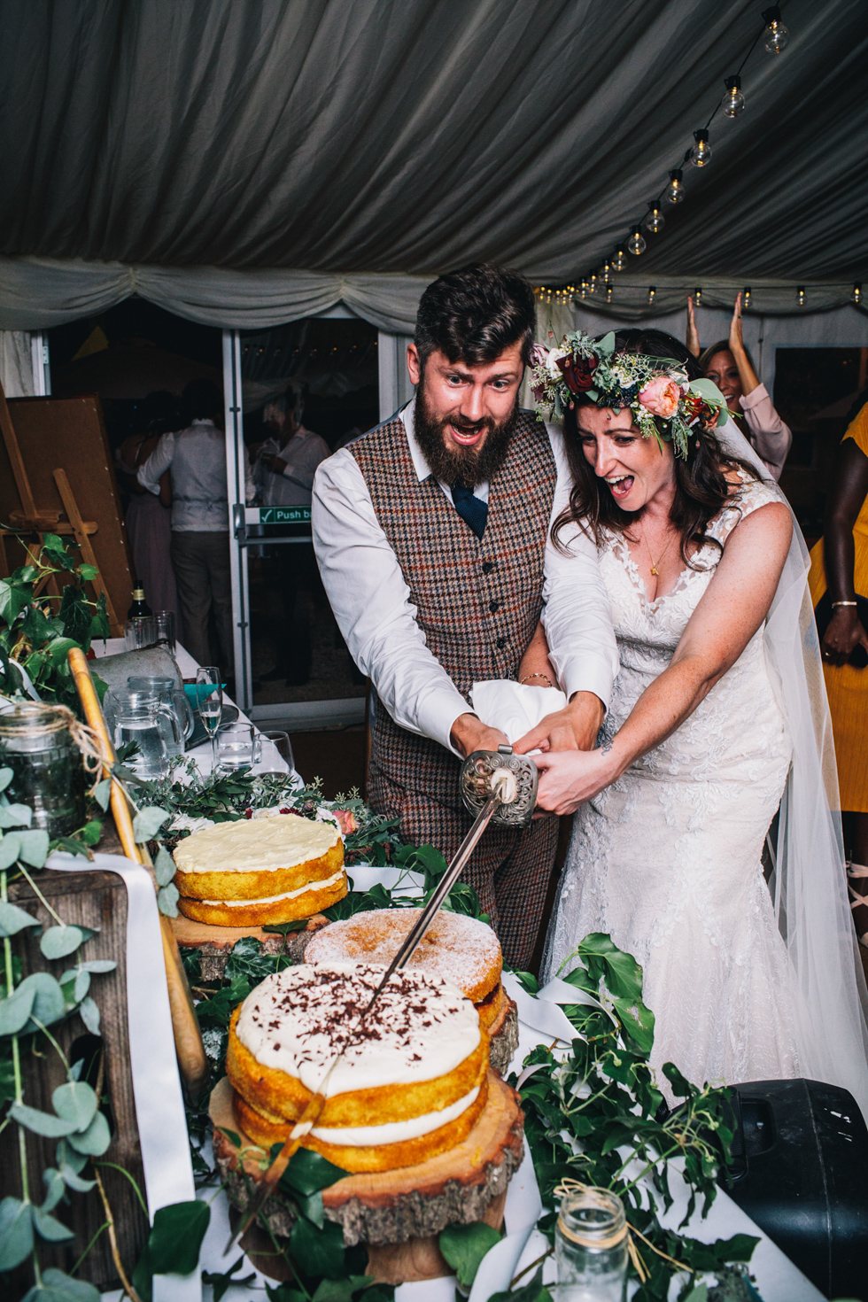 quirky fun bride and groom cutting the cake with a huge sword