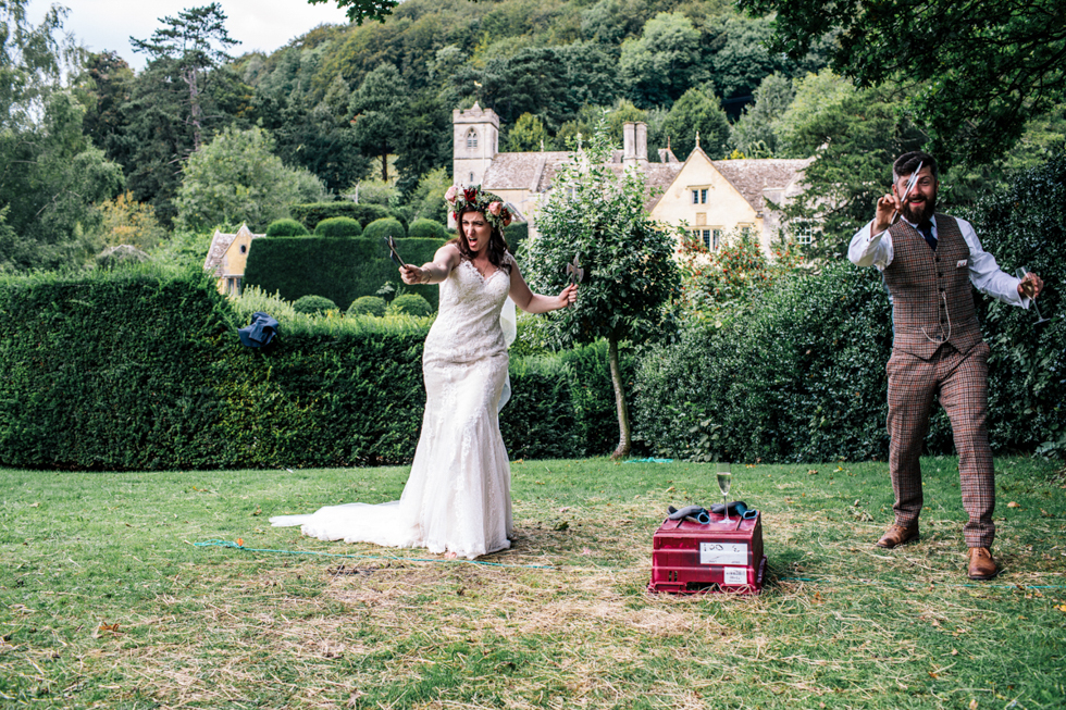 fun alternative quirky bride and groom taking part in the axe throwing competition at Owlpen Manor festival wedding