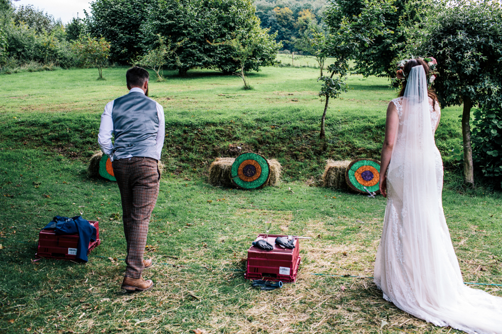 fun alternative quirky bride and groom taking part in the axe throwing competition at Owlpen Manor festival wedding