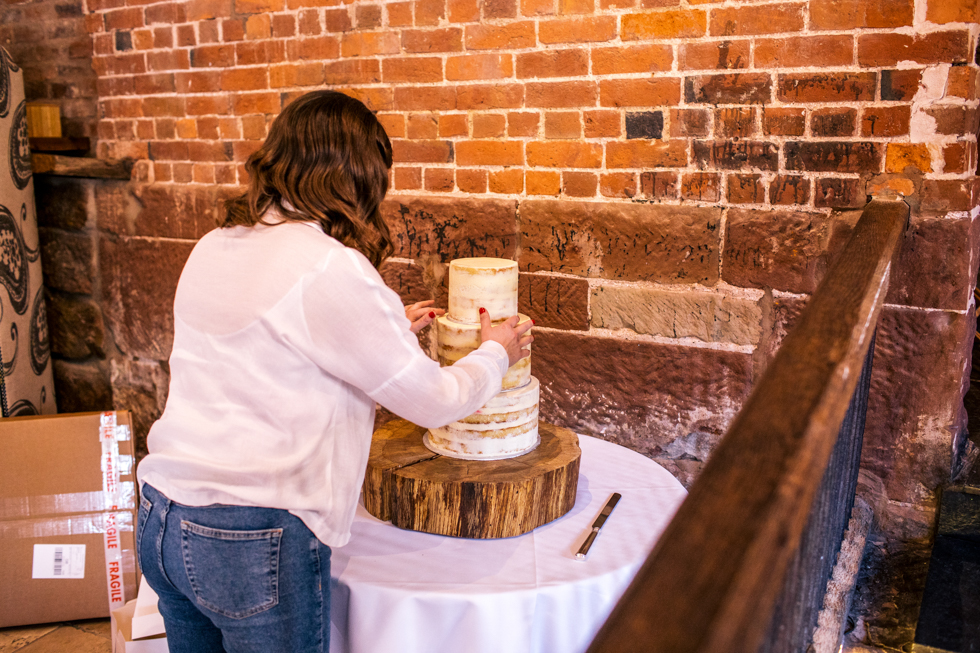 bride setting up wedding cake at Curradine barns 