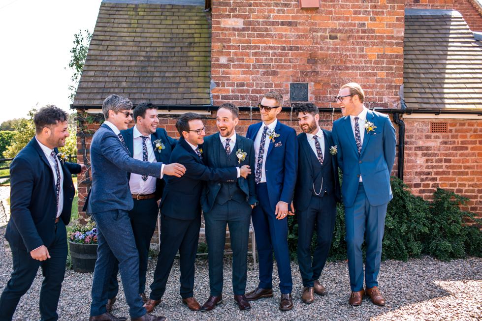 groom and mates messing about next to brick wall at Curradine barns