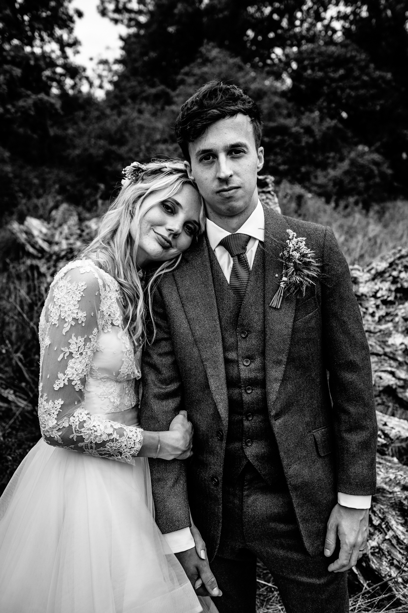 bride in lace Emma Tindley separate top and groom in navy blue and red tie three piece suit snuggled together for couple portrait at wedding in Mells walled garden