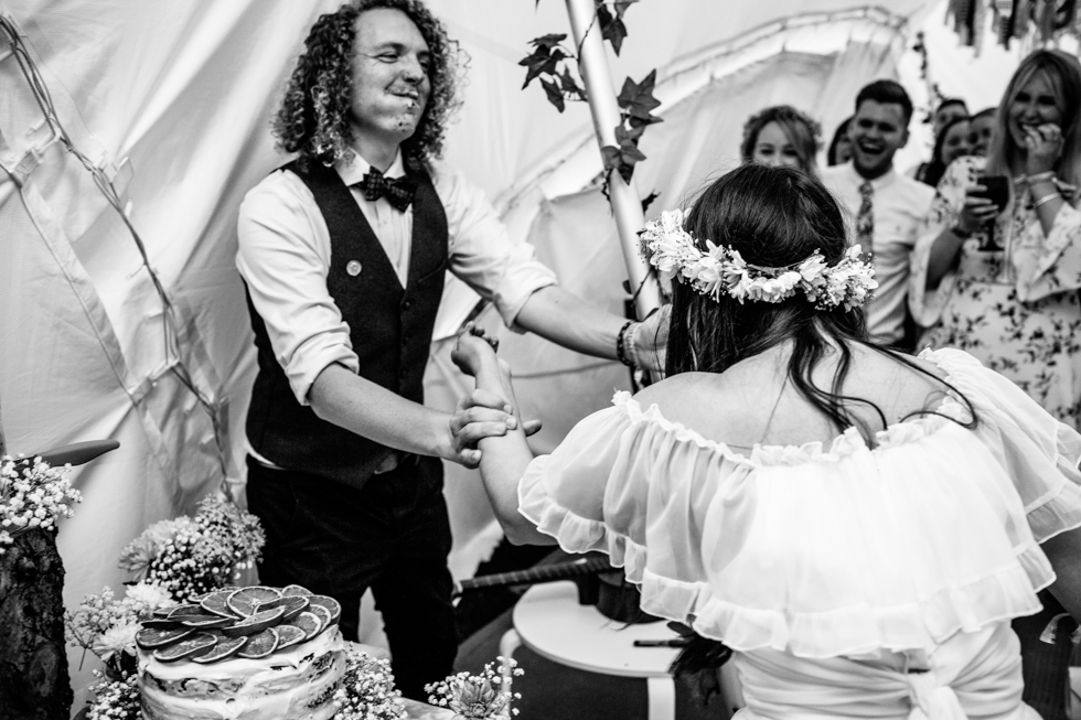 bride shoving cake into grooms face in food fight at festival wedding