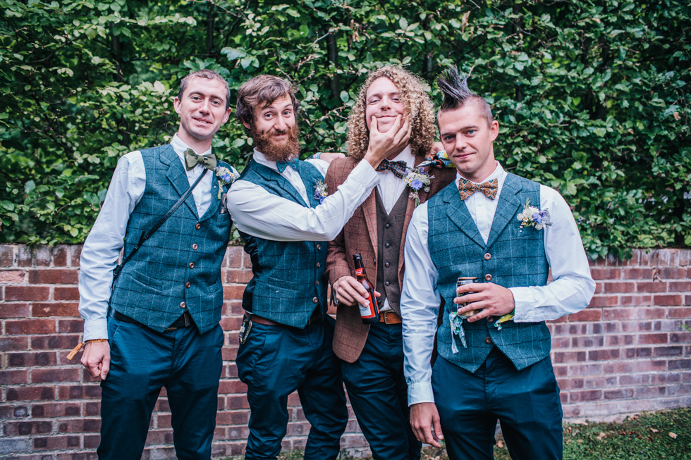 boys messing about in group shot at festival wedding wearing tweed
