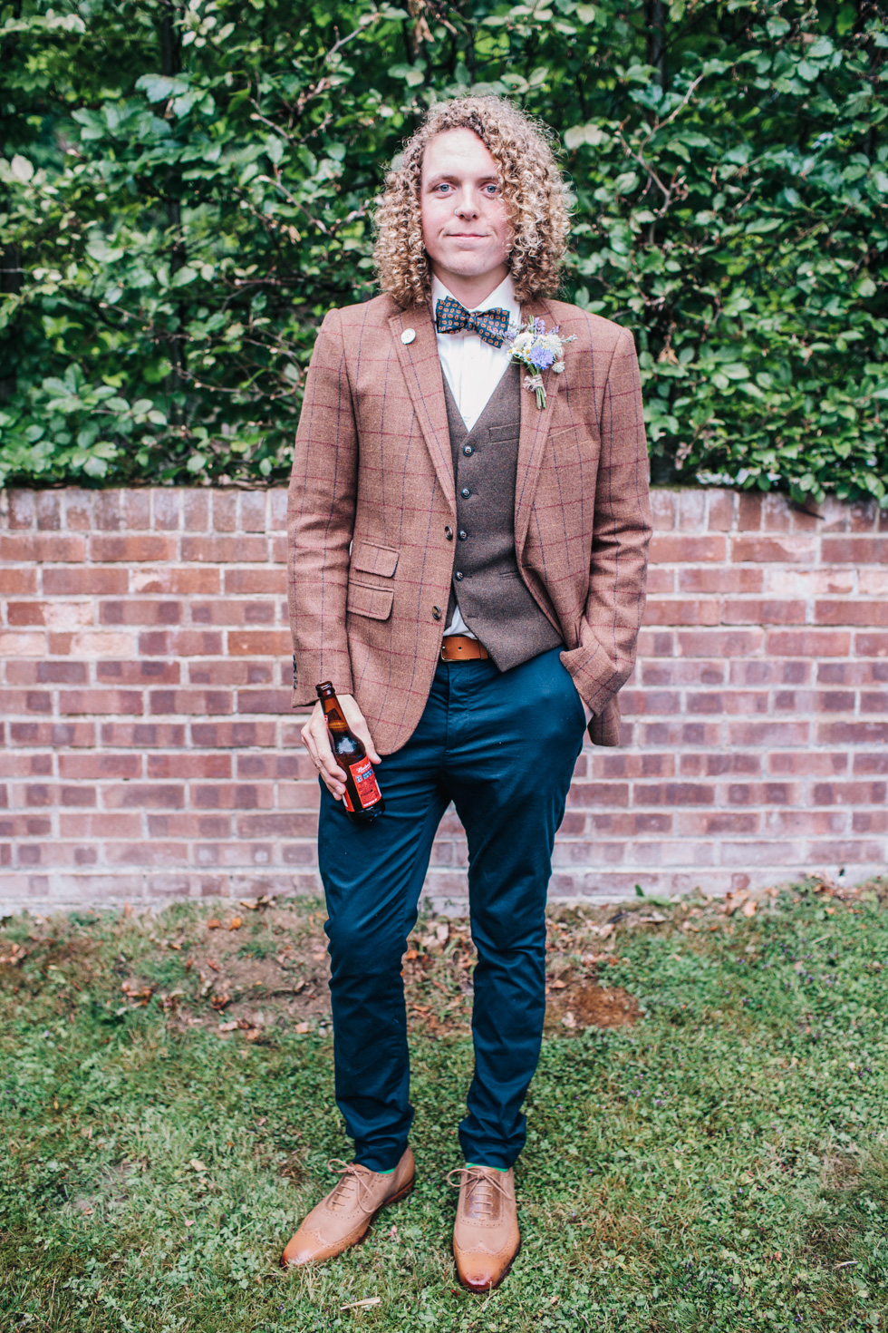 groom wearing brown check tweed and bowtie at festival wedding 