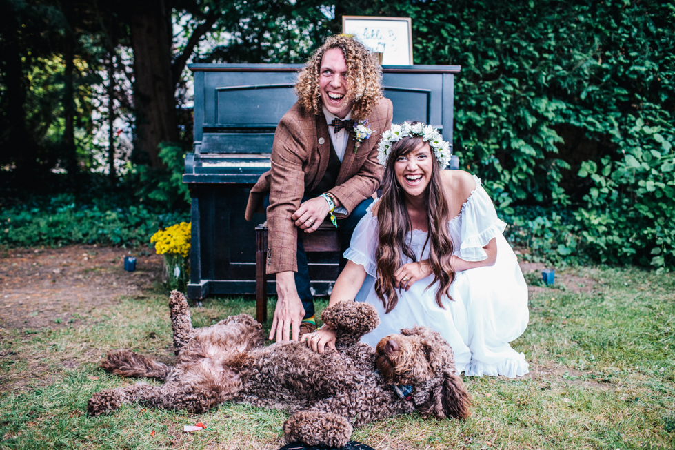 bride and groom with their dog in group shot taken outside in front of old piano 