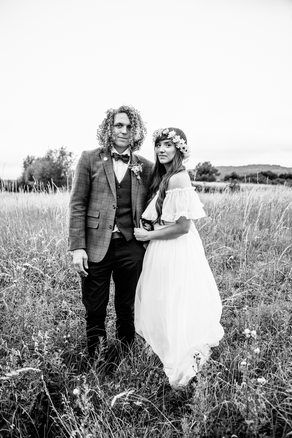 couple portrait of bohemian bride and long haired groom walking through fields at festival wedding heart full of tea top tips