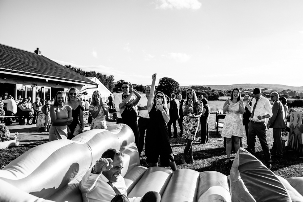 wedding guests having fun using surf machine at alternative wedding at Quantock Lakes