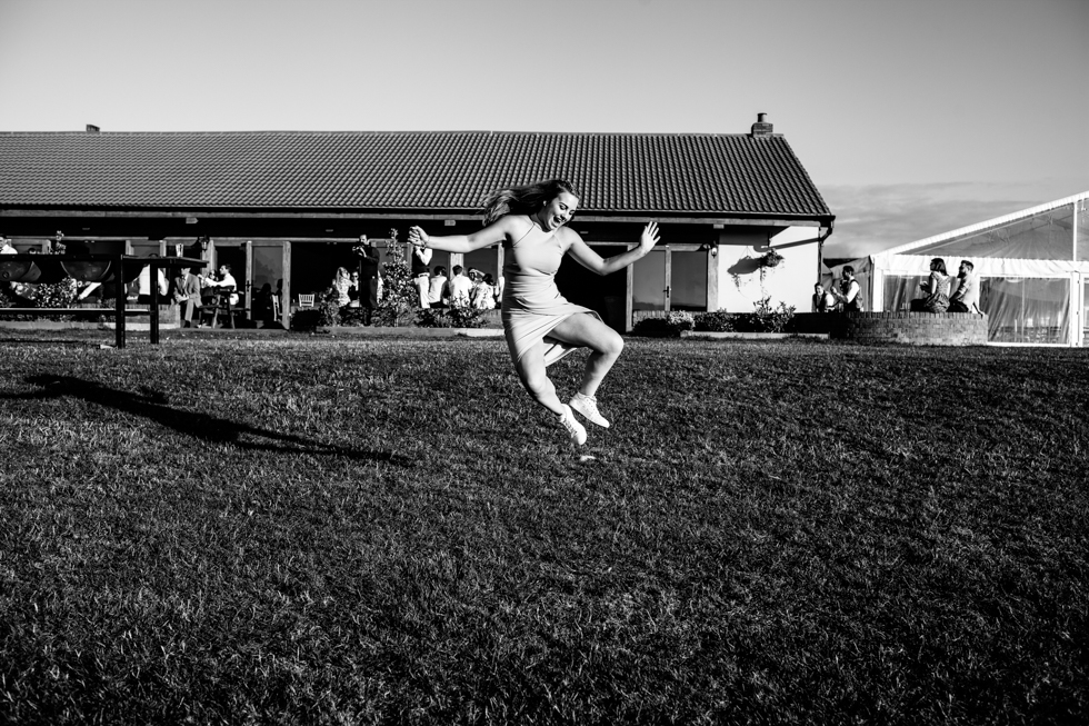 wedding guest jumping and clicking feet together down a hill at Quantock Lakes