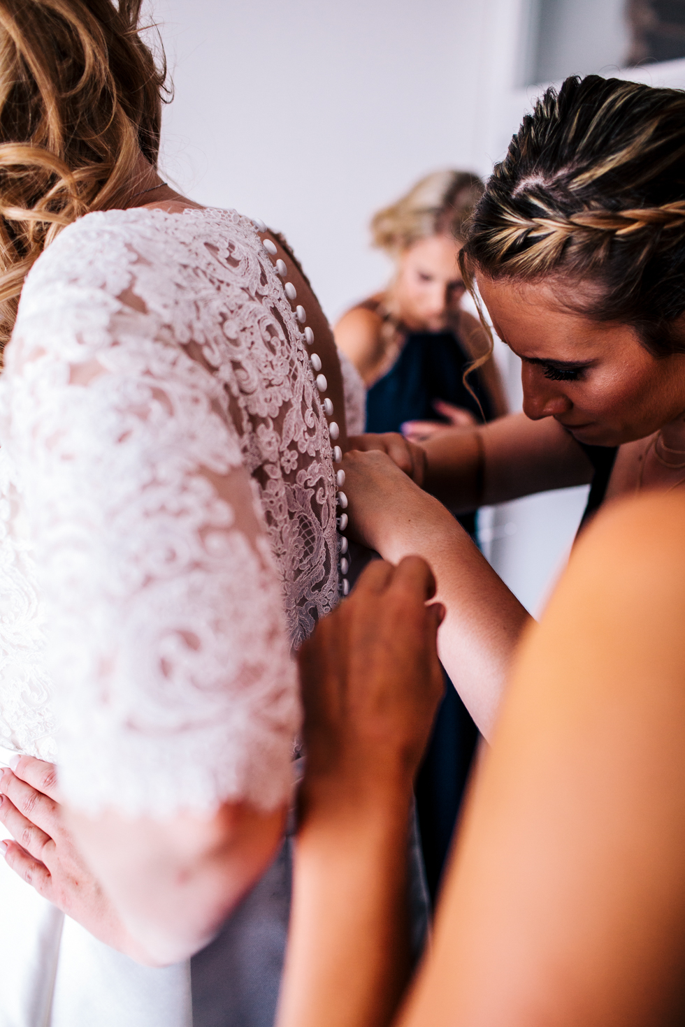 bridesmaids helping with buttons on brides dress
