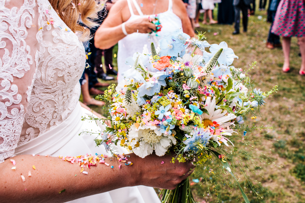 bride holding beautiful wild flowers for her bouquet covered in confetti 