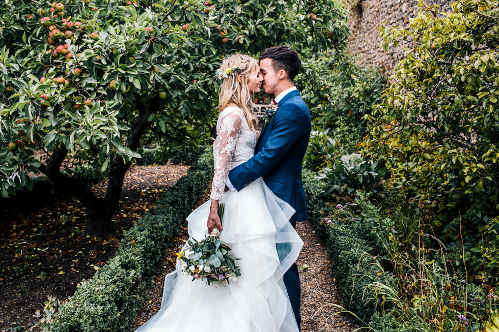 bride and groom kissing under apple orchard at Mells walled garden