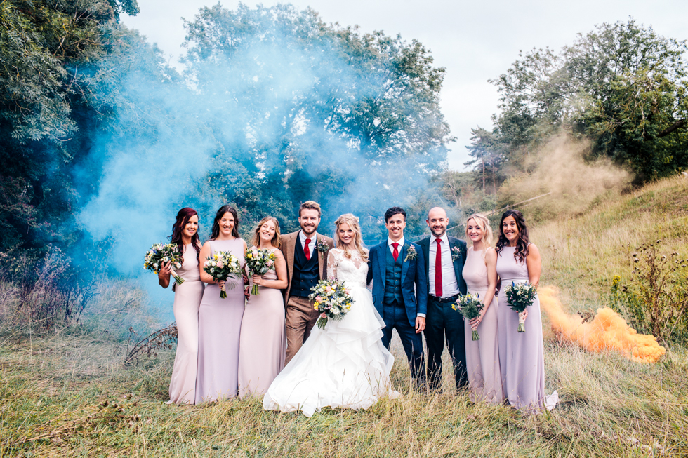 blue and orange stylised photo of smoke bomb with bride groom and friends at a wedding in Mells frome