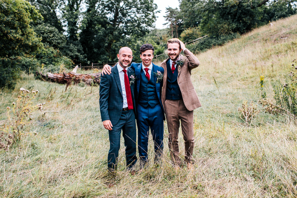 groom best man and usher laughing and messing about in a field for their own special photo at wedding near Mells frome