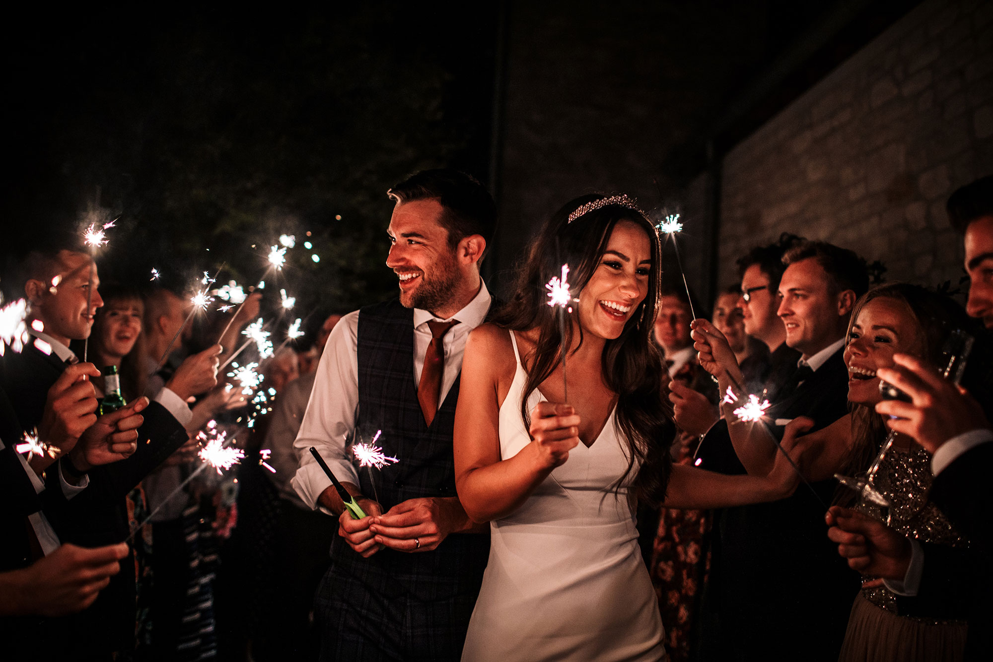 Bride and groom walking holding sparklers late at night in bath