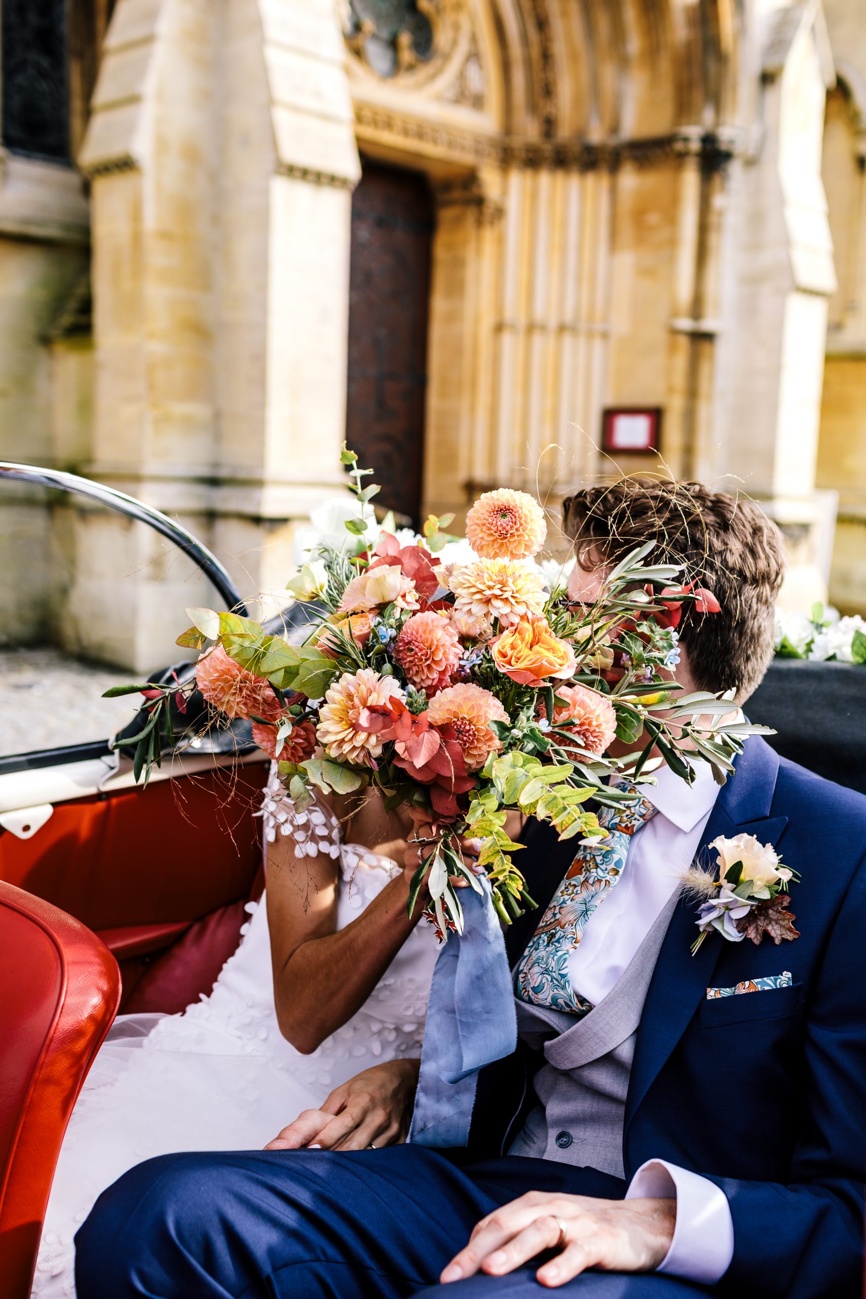 bride and groom kissing behind beautiful autumn wedding flowers