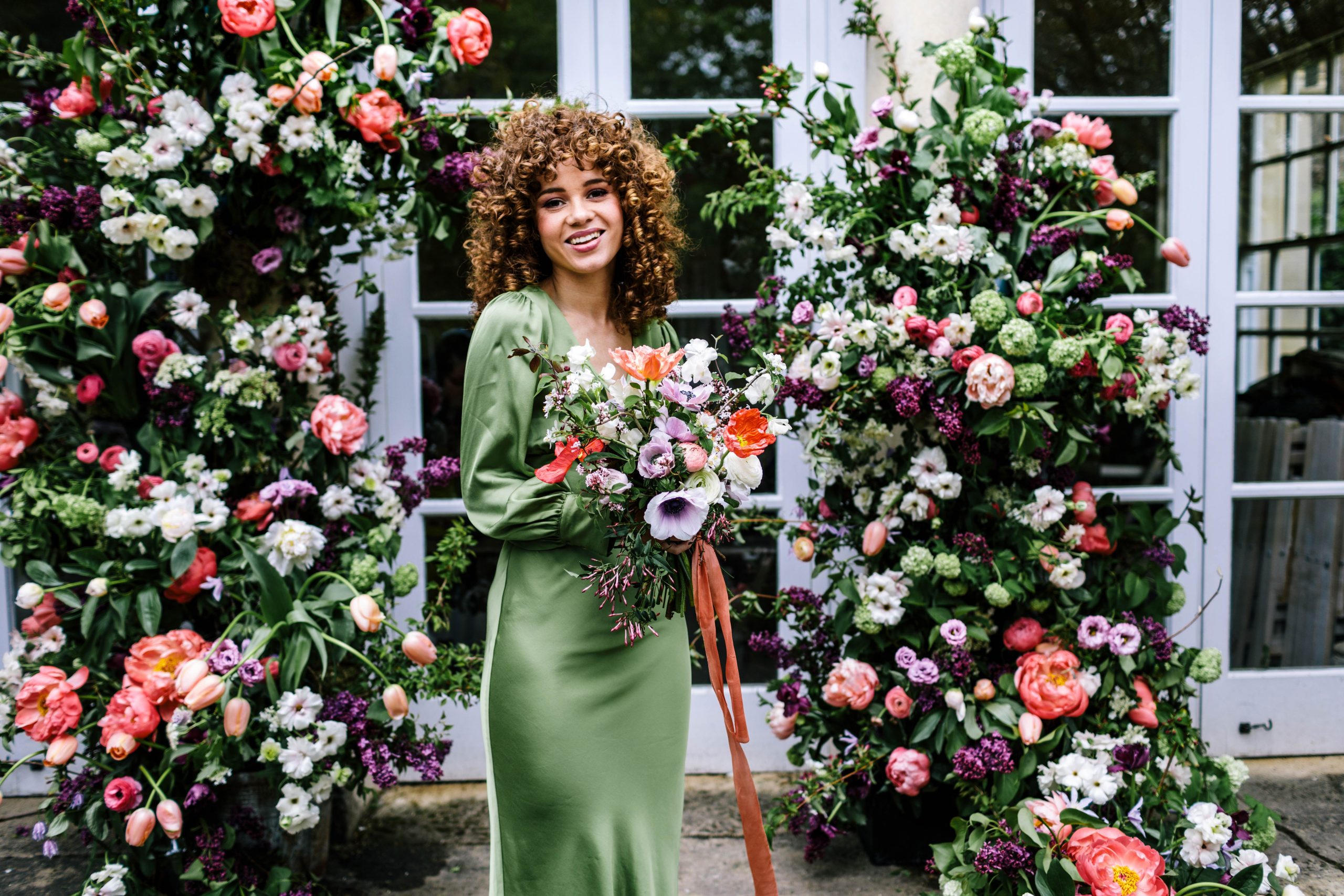 bride in green wedding dress surrounded by flowers at Bath venue